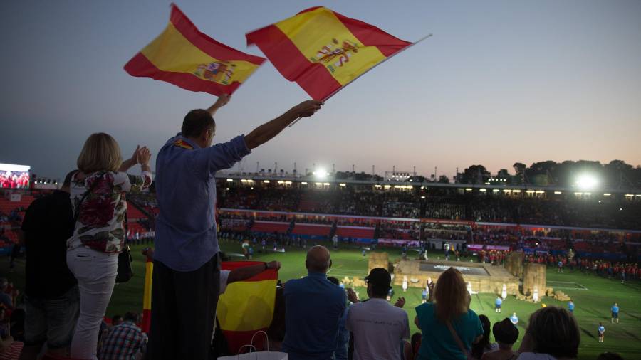 Dos personas agitan banderas al paso de los atletas españoles durante la inauguración de los XVIII Juegos Mediterráneos
