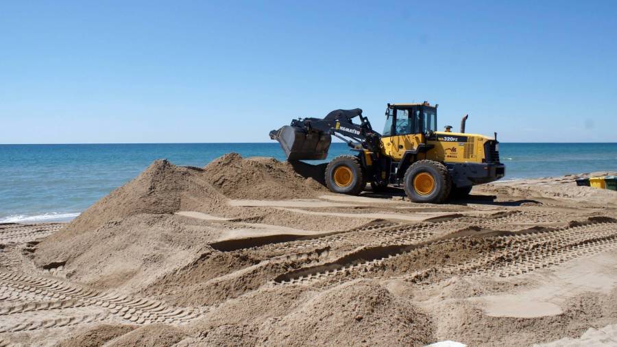 Una excavadora extiende la arena.