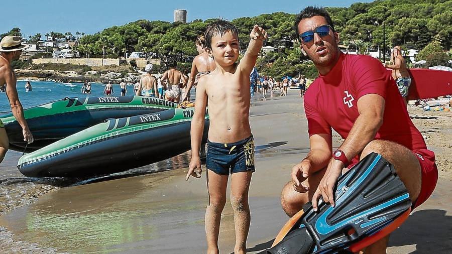 Adrià ayudando un niño en la playa de La Mora (Tarragona). FOTO: Alba Mariné