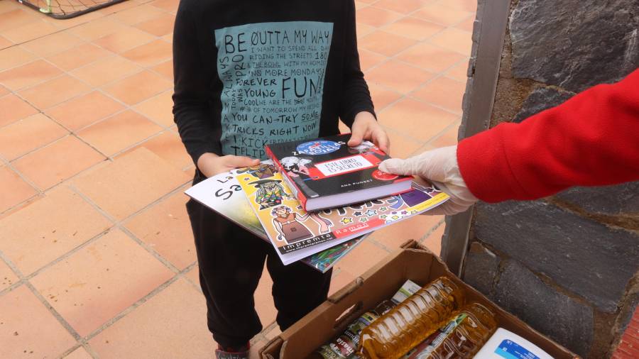 Imatge d'arxiu d'un nen agafant llibres d'un voluntari. FOTO: ACN