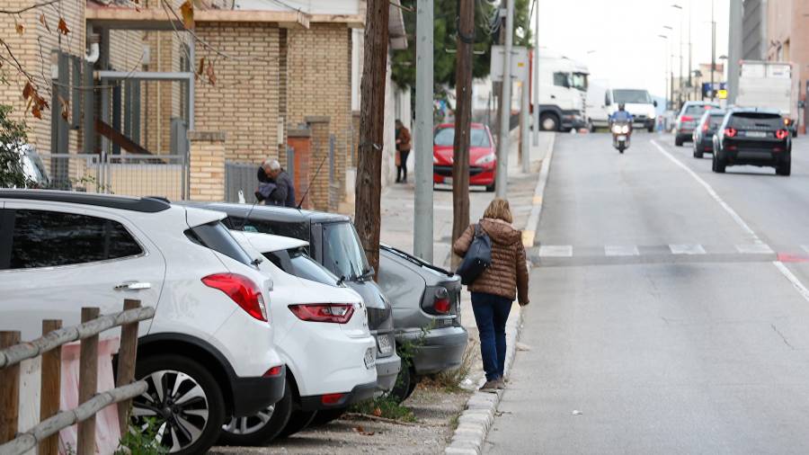 Imagen de una persona haciendo equilibrios para no pasar por la carretera ante la ausencia de una acera marcada. FOTO: PERE FERRÉ