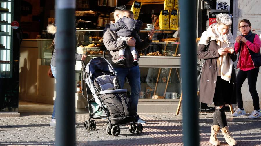 Un hombre, con un niño en brazos y un carrito, en el centro de Tarragona. Los expertos destacan el aumento de la conciliación. FOTO: pere ferré