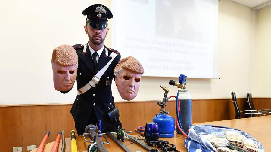 Un miembro de los Carabinari muestra unas máscaras con la imagen del presidente de Estados Unidos, Donald Trump, usadas por dos ladrones. Foto: EFE