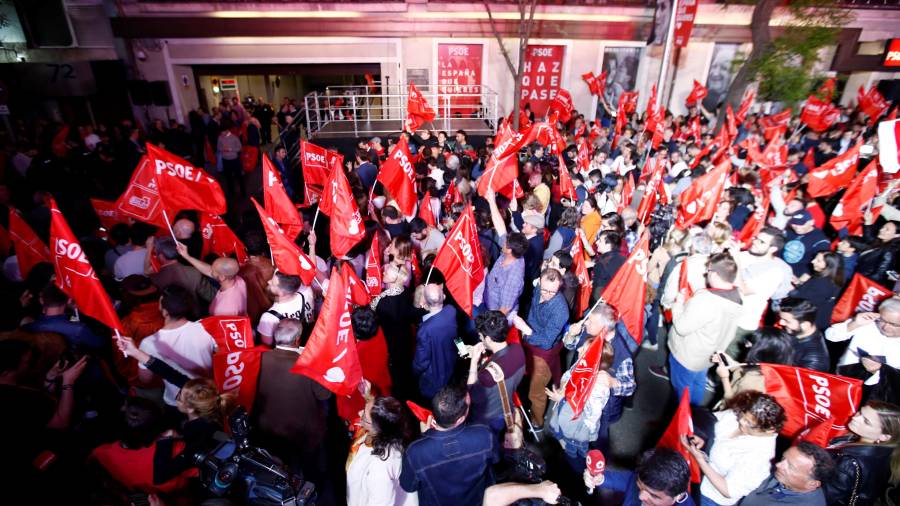 Personas congregadas a las puertas de la sede del PSOE en Madrid desde donde siguen el escrutinio de las elecciones. FOTO: EFE