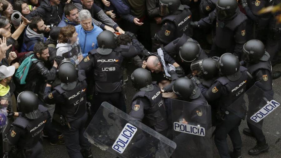 Agentes antidisturbios de la Policía Nacional forman un cordón de seguridad frente al colegio Ramón Llull de Barcelona. FOTO: EFE