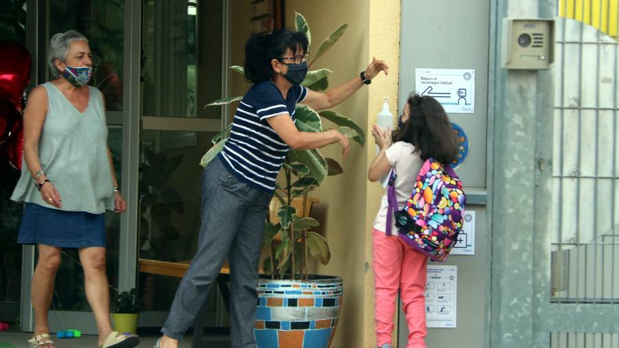 Imatge d'una nena desinfectant-se les mans amb gel hidroalcohòlic a la porta de l'escola Joan Juncadella el 17 de setembre de 2020. (Horitzontal)