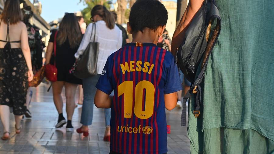 Un niño con la camiseta de Messi pasea de la mano de su madre en Salou. El argentino ya no jugará más de azulgrana. Foto: Alfredo González