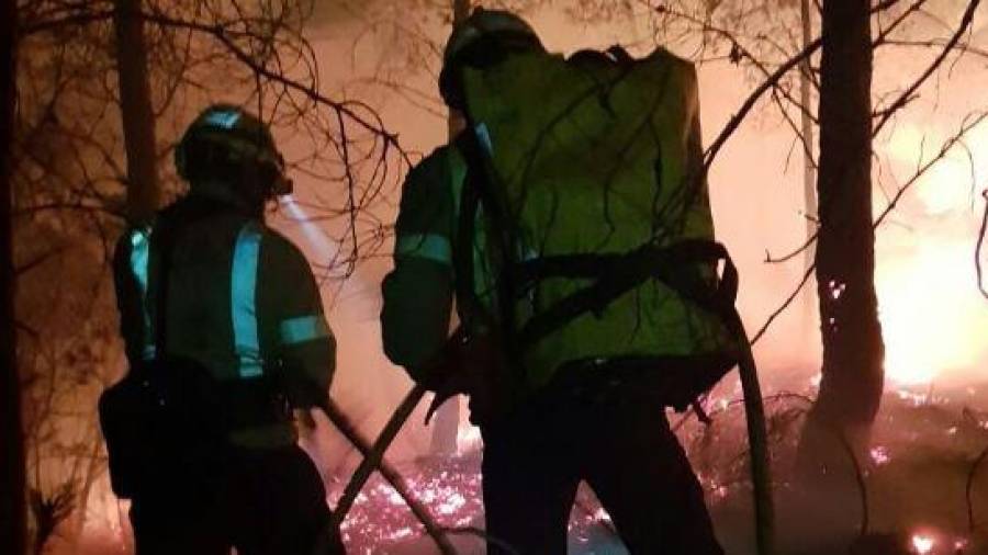 Dos bomberos apagando las llamas del incendio forestal de Benifallet. FOTO: Bombers