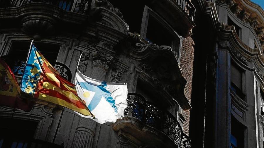 Detalle de la fachada de la sede social de Caixabank con la bandera de entidad y la de la Comunitat Valenciana ondeando al viento. FOTO: efe