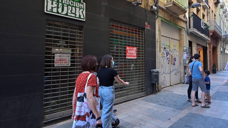 Gente paseando ante un comercio cerrado en la calle de les Galanes, justo tocando con la plaza del Mercadal. FOTO: Alfredo González