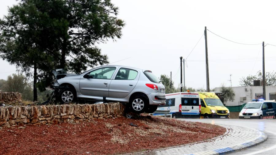 El cotxe suspès sobre el marge de pedra de la rotonda després d'impactar contra un pi. foto: ACN