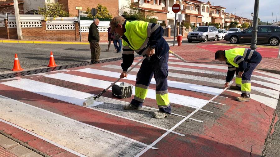 Operaris de la brigada municipal de Roda de Berà repintant un pas de peatons.