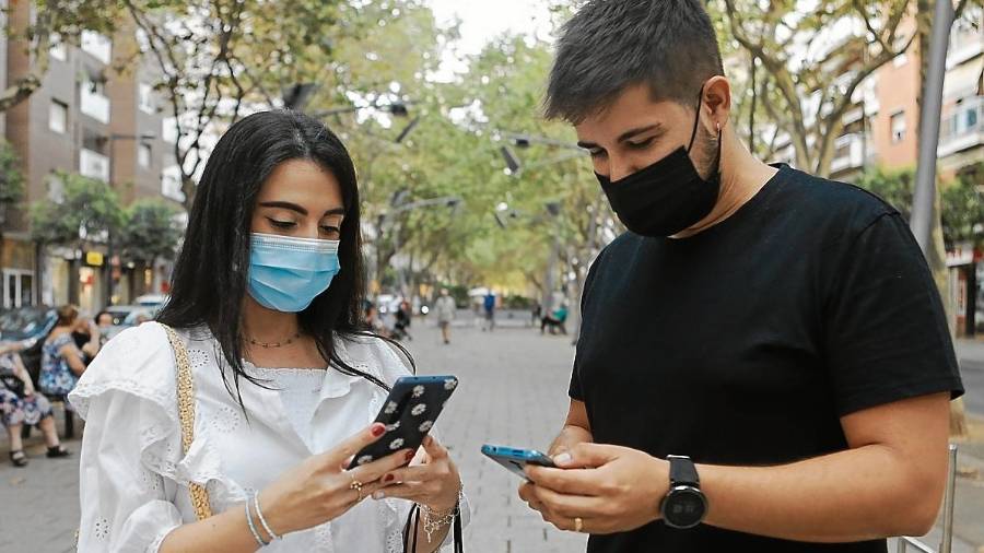 Dos jóvenes atendiendo a sus móviles, en el Passeig Prim de Reus. Foto: Alba Mariné