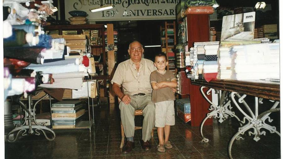Ramon Creus, con su nieto Guillem, dentro de la tienda en una imagen de hace años. FOTO: Cedida