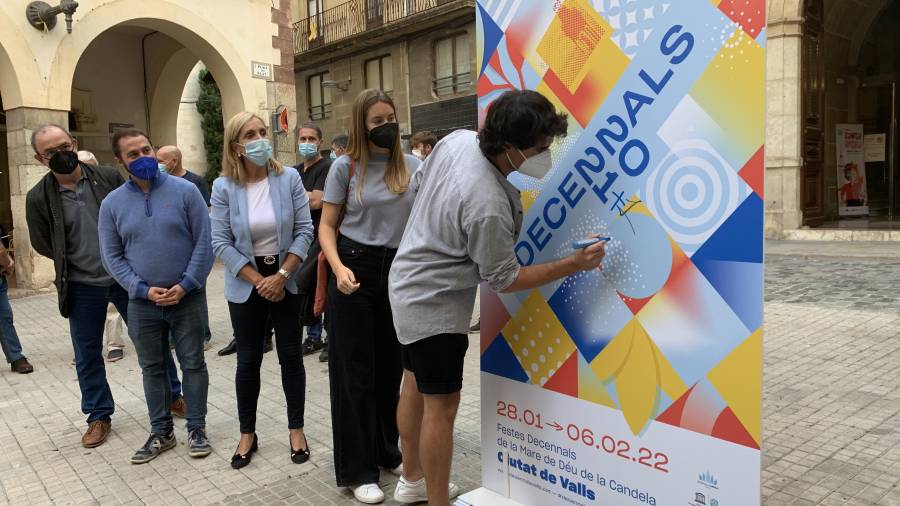 Els dissenyadors Adrià Batet i Ariadna Pujol van acabar ahir el cartell en directe a la plaça del Blat de Valls on van afegir el ‘+1’ que indica el caràcter excepcional d’aquesta edició de les Decennals. FOTO: J. G.