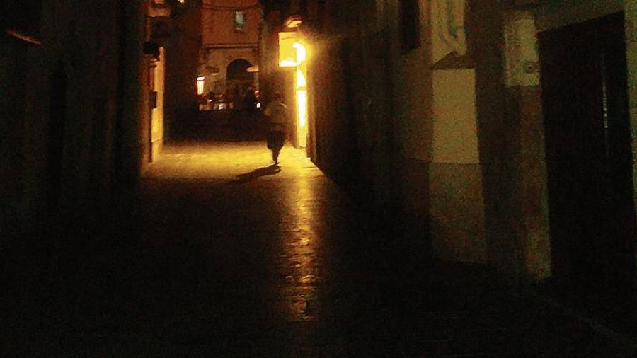 La calle Ventallols completamente a oscuras, excepto por la luz de uno de los restaurantes.