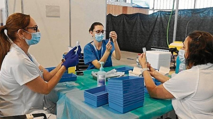 Tres enfermeras preparan dosis en el Palau d’Esports de la Anella Mediterrània del barrio de Campclar. Foto: Alfredo González
