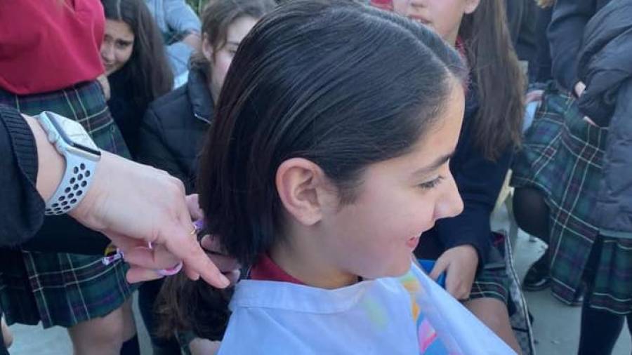Una joven se corta el cabello por la causa solidaria.