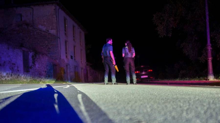 Dos agentes de la Guardia Civil cortan la carretera que da acceso al lugar en el que un hombre lleva atrincherado desde las 21.00 horas de este martes. EFE