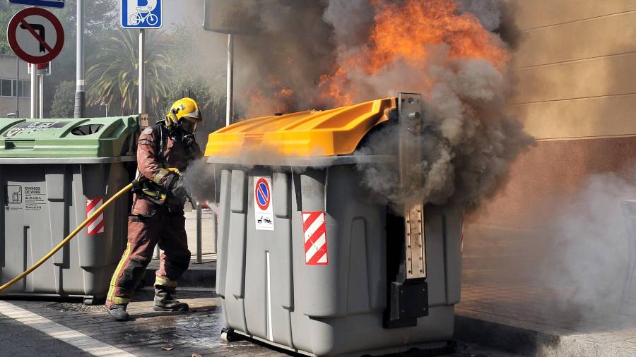 Imagen de archivo de un bombero apagando el fuego de un contenedor de la calle Ample de Reus. Foto: A. González
