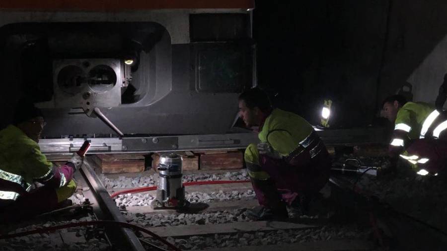 Técnicos de Renfe trabajando para encarrilar el tren accidentado en el túnel de Toses.