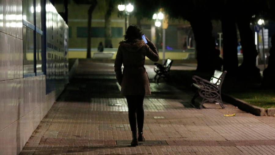Una joven camina sola de noche por una calle de Tarragona. Hablar por el móvil es una medida de seguridad. FOTO: pere ferré