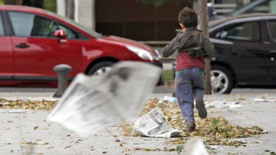 Imatge d'arxiu d'un nen que corre pel carrer enmig d'una forta ratxa de vent. Foto: DT