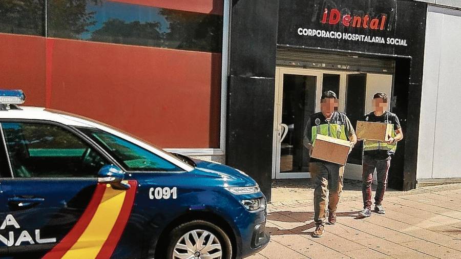 Dos agentes de la Policía Nacional llevándose cajas con material de iDental. FOTO: Àngel Juanpere
