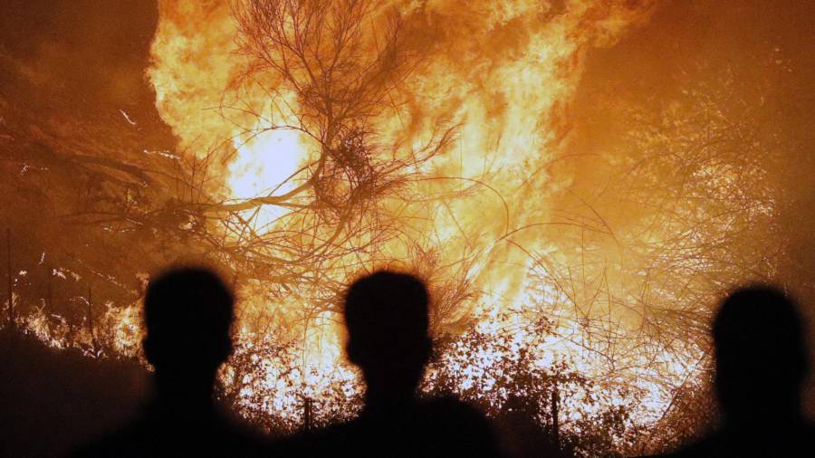 Unes persones observen un incendi a Chandebrito (Galícia), dilluns passat. Foto: EFE