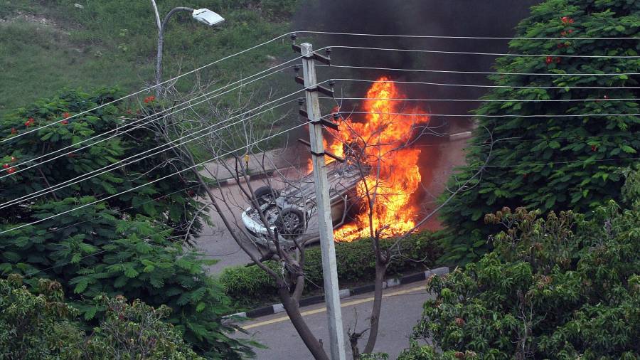 Vista de un coche en llamas durante disturbios en Panchkula (India)