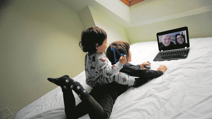 Dos niños conversan con sus abuelos mediante una videollamada en su casa. Foto: EFE