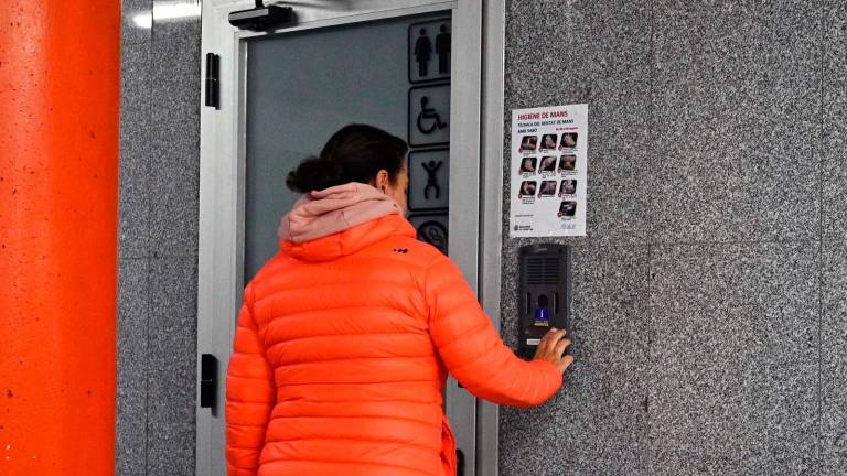 Una mujer pulsando el timbre para acceder a los baños del parking municipal de la Llibertat. Foto: Alfredo González